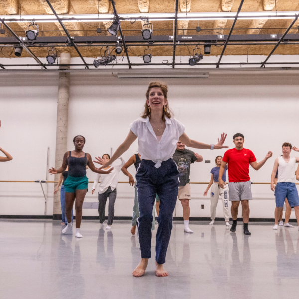A diverse group of students in a WashU dance class, dressed in comfortable workout attire, practicing choreography together.
