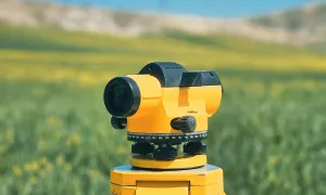 Survey tool set up on a tripod in a scenic field.