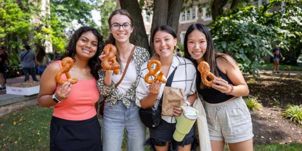 A&S students pose for a photo while holding Ampersand-shaped pretzels.