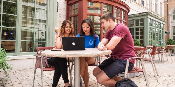 Three students gather around a computer in the South40.