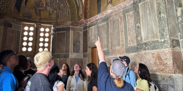 Three people hold a recreation of an original painting in their hands and run their hands across the surface of the canvas as part of Saint Louis Art Museum's 