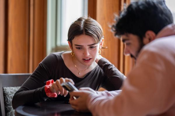 Emma Lembke, center, shares a mobile phone with a fellow student as they examine and discuss the screen's contents together.